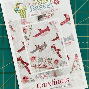May include: A white and red quilt pattern featuring cardinals with the title "Cardinals" and the website "www.thepatternbasket.com". The pattern is from "The Pattern Basket" by Margot Languedoc Designs.