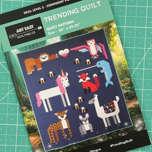 May include: A quilt pattern featuring a variety of animals, including a unicorn, a sloth, a fox, a llama, a cheetah, and an owl. The pattern is on a dark blue background with white and pink accents. The quilt is 60 inches by 69.25 inches. #TrendingQuilt