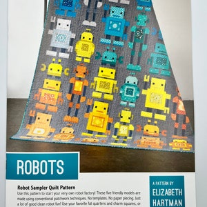 May include: A quilt pattern titled "ROBOTS" featuring a gray background with colorful robot designs. The robots are in various colors, including blue, yellow, orange, and teal. The pattern is by Elizabeth Hartman and is for a robot sampler quilt.