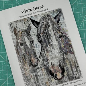 May include: A white horse and a foal, both with black eyes, are depicted in a collage style using newspaper clippings and other paper scraps. The artwork is titled "White Horse" and is signed by Laura Heine. The size of the artwork is 36 inches wide by 47 inches high.