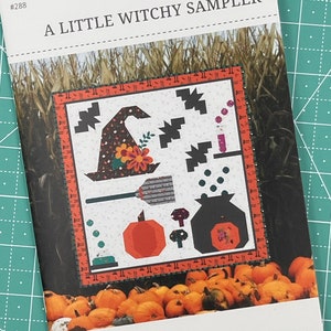 May include: A quilt pattern titled "A Little Witchy Sampler" by Sew A Story. The pattern features a witch's hat, broom, cauldron, pumpkin, and mushrooms. The finished quilt size is 41 inches by 42 inches.