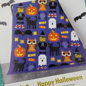 May include: A quilt pattern called "Happy Halloween" by Elizabeth Hartman. The pattern features a sampler quilt with a variety of Halloween characters and objects, including a witch, a cat, a pumpkin, an owl, a spider, candy corn, and a ghost. The quilt is made using conventional patchwork techniques.