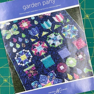 May include: A blue booklet with the title "garden party" and the text "Piece an elegant celebration of spring in two delicious palettes!" The cover features a colorful quilt with a floral design.