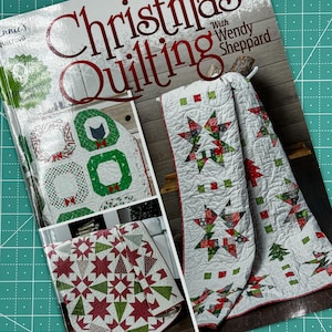 May include: A magazine cover featuring Christmas quilting projects. The cover features a red and green quilt with a star design, a green and red wreath quilt, and a red and green quilt with a tree design. The text on the cover reads "Christmas Quilting with Wendy Sheppard".