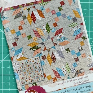 May include: A quilt pattern booklet featuring a colourful quilt design on the cover. The title of the pattern is "Upbeat" and the designer is Jocelyn Ueng. The booklet includes sizes for small lap, large lap, twin, and queen quilts.