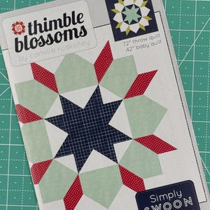 May include: A quilt pattern featuring a starburst design in red, white, and green. The pattern is called "Simply Swoon" and is available in two sizes: a 72-inch throw quilt and a 42-inch baby quilt.