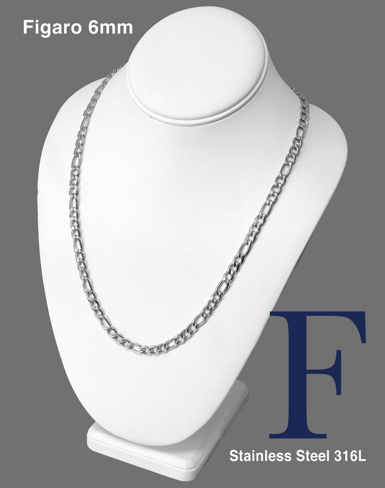 May include: A silver Figaro chain necklace on a white display stand. The chain is 6mm wide and made of stainless steel 316L.