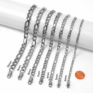 May include: A set of eight silver chain necklaces of varying widths, ranging from 4mm to 10mm. The chains are laid out on a white surface, with the width of each chain labelled in millimetres.