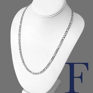 May include: A silver Figaro chain necklace with a 5mm width, made of stainless steel 316L. The chain is displayed on a white mannequin.