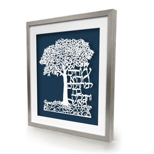 May include: White papercut art of a tree with Hebrew text on a dark blue background, framed in silver.