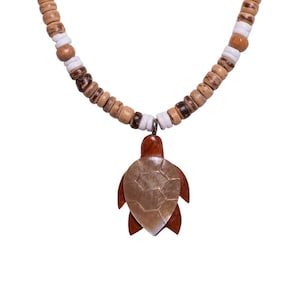 May include: A wooden necklace featuring a turtle pendant. The pendant is brown with a light-colored shell design. The necklace has a strand of wooden beads in shades of brown and white.