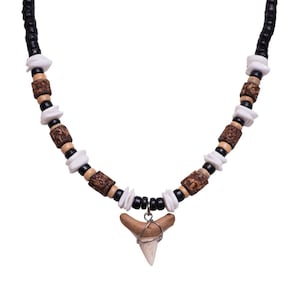 May include: A necklace made of brown, black, and white beads with a shark tooth pendant.