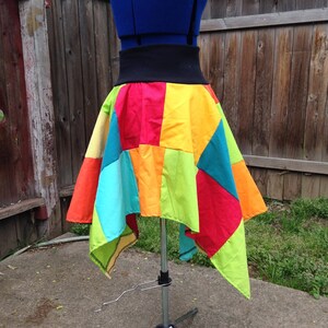 K&ouml;nnte beinhalten: Ein bunter Patchwork-Rock mit einem schwarzen Bund. Der Rock besteht aus verschiedenen Stoffen in verschiedenen Farben, darunter Rot, Orange, Gelb, Gr&uuml;n, Blau und T&uuml;rkis. Der Rock ist asymmetrisch, eine Seite ist l&auml;nger als die andere.