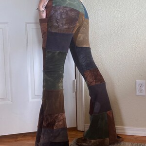 Op de afbeelding: Patchwork broek met uitlopende pijpen, gemaakt van diverse aardetinten in bruin, olijfgroen, antraciet en beige. De broek heeft een hoge taille, wijd uitlopende pijpen en zichtbare zijzakken, opgebouwd uit verschillende panelen met diverse texturen.