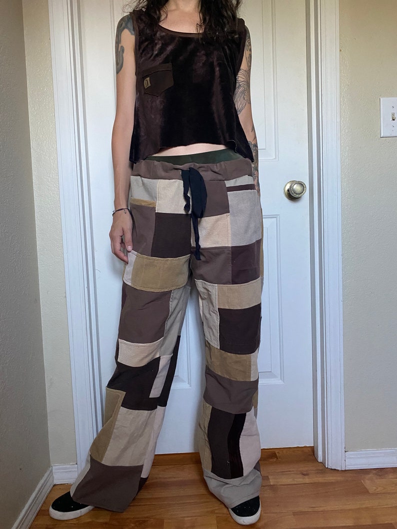 K&ouml;nnte beinhalten: Ein braunes Samttop mit kleiner Tasche und Patchwork-Hose in Braun-, Beige- und Beiget&ouml;nen. Die Hose hat einen Kordelzug in der Taille und ein weites Bein. Das Outfit ist l&auml;ssig und b&ouml;hmisch.