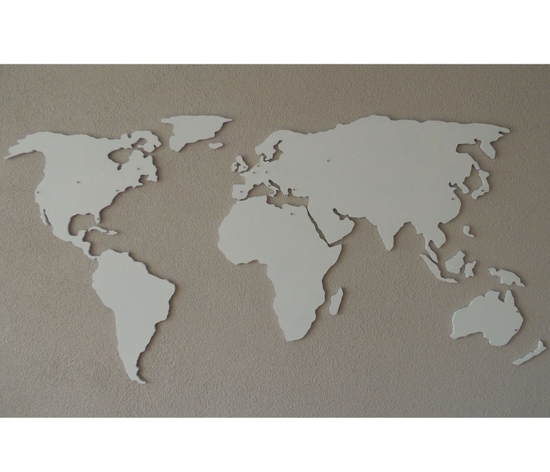 Puede incluir: Un mapa del mundo de madera blanca recortado, montado en una pared beige. El mapa es un simple contorno de los continentes y oc&eacute;anos.