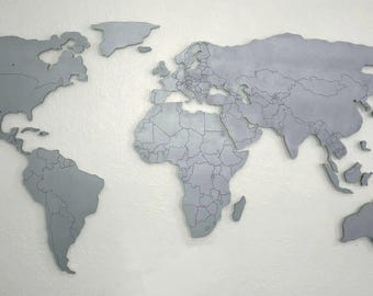 Mapa del mundo magnético de madera XL con bordes de países grabados, en negro, blanco, plateado o color personalizado, que parece flotar en la pared.
