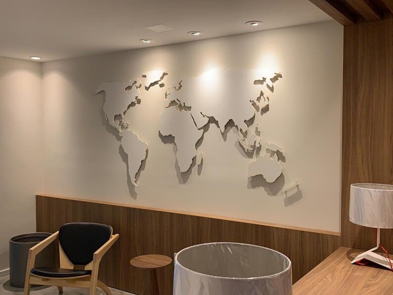 Puede incluir: Una pared blanca con un recorte de un mapa del mundo. El mapa est&aacute; en una pared con paneles de madera debajo. Hay una silla y una mesa en la habitaci&oacute;n.