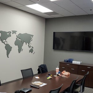 Puede incluir: Una sala de conferencias con un gran mapa del mundo gris en la pared, una larga mesa de madera marr&oacute;n con sillas, dos televisores de pantalla plana grandes, un armario con cajones y un peque&ntilde;o refrigerador.