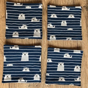 K&ouml;nnte beinhalten: Set mit vier blauen und wei&szlig;en Stoffuntersetzern mit einem Muster aus wei&szlig;en Ottern auf einem blau-wei&szlig; gestreiften Hintergrund.
