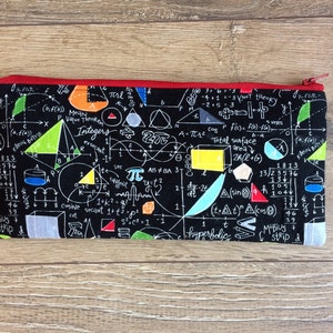 Op de afbeelding: Een zwarte etui met rits met een kleurrijke print van wiskundige vergelijkingen, formules en geometrische vormen. De print bevat getallen, symbolen en woorden zoals "gehele getallen", "cosinus", "secans", "pi", "hyperbolisch" en "Möbiusband".