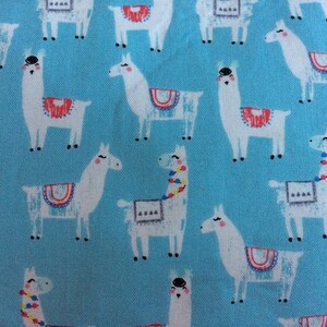 May include: A blue fabric with a repeating pattern of white llamas. The llamas have colorful details on their saddles and some have colorful beads around their necks.