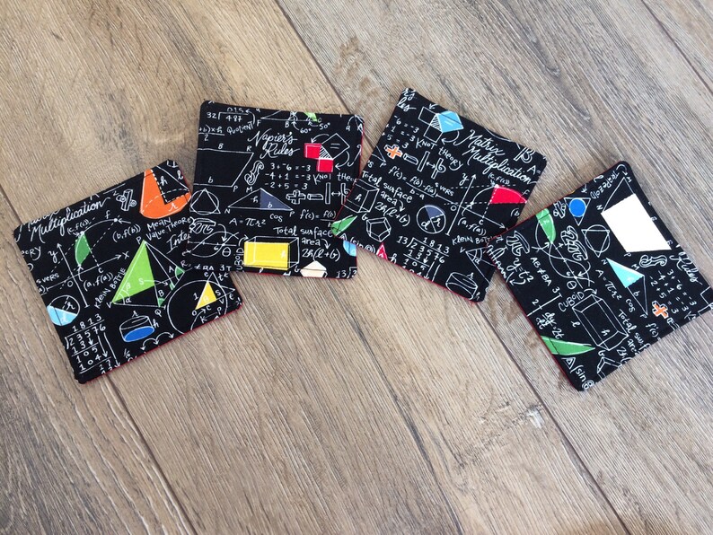 May include: Four black and white coasters with a red border. The coasters feature a variety of geometric shapes and mathematical equations. The text on the coasters includes "Multiplication", "Inter Rules", and "Total surface".