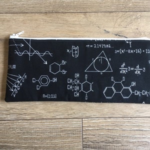 Peut inclure: Une trousse à crayons noire à fermeture éclair avec un imprimé blanc de diverses formules mathématiques et structures chimiques. L'impression comprend des équations, un graphique, un triangle avec un cercle à l'intérieur et des structures chimiques avec des étiquettes comme "Br" et "OH".