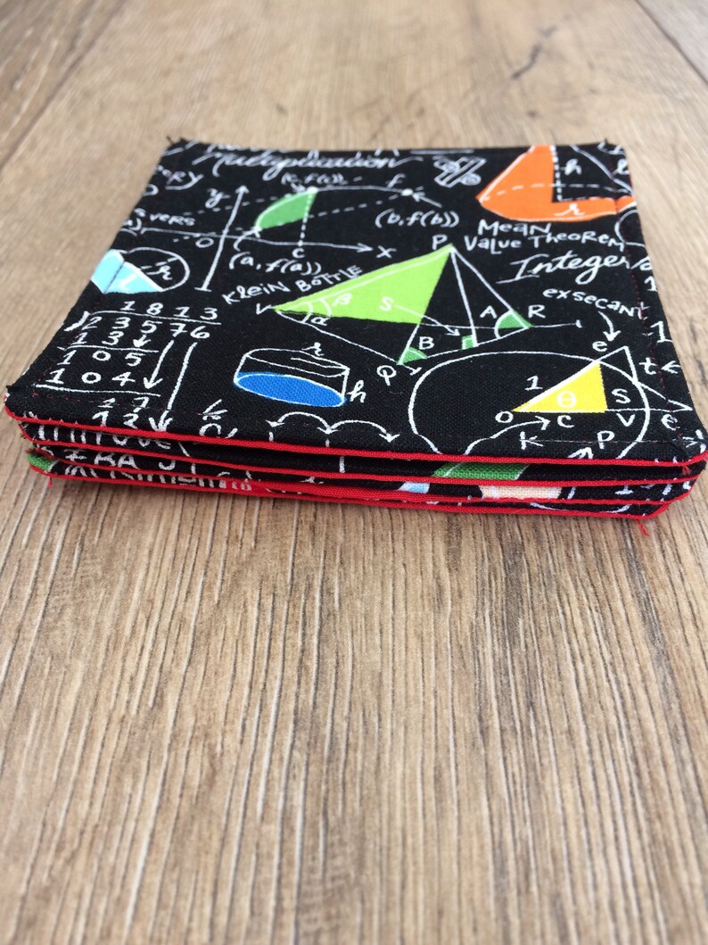 May include: A stack of four black coasters with a red border. The coasters feature a white design of mathematical equations, geometric shapes, and the words "Klein Bottle", "Mean Value Theorem", and "Integer".