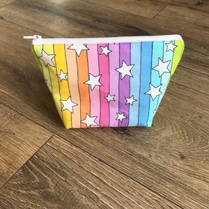 Op de afbeelding: Een regenboogkleurige, met een rits uitgeruste tas met witte sterren erop.