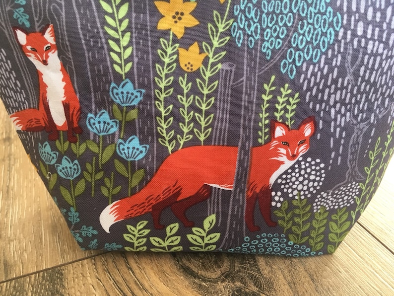 May include: A gray fabric tote bag with a repeating pattern of orange foxes, green leaves, and blue flowers.