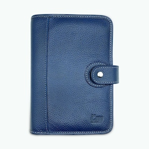 Op de afbeelding: Een blauw leren notitieboek met een getextureerd oppervlak en witte stiksels. Het notitieboek heeft een druksluiting en een klein logo rechtsonder. Het rechthoekige notitieboek lijkt gesloten.