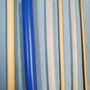 May include: Seven different colored dowels, including blue, white, and natural wood, are arranged vertically against a blue background.