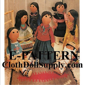May include: A group of seven handmade cloth dolls dressed in Native American inspired clothing. The dolls are sitting on a rug with a woven basket and a cradle. The dolls are all different sizes and have different facial features. The dolls are all wearing traditional clothing and jewelry. The dolls are all made of cloth and have a rustic, handmade look. The image includes the text "E-PATTERN ClothDollSupply.com".