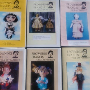May include: Six colorful paperbacks with the title "Frowning Francis Folk Art Patterns" and illustrations of dolls. Each book features a different doll design.