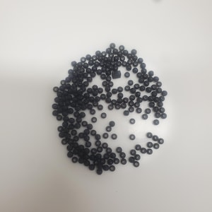 May include: A large quantity of small, black round beads, scattered on a white surface.
