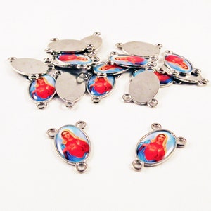 May include: A collection of silver-toned metal connectors with oval-shaped inserts. Some inserts feature a religious image of a woman with a red heart and blue background. The connectors have three small loops for attaching to other components.