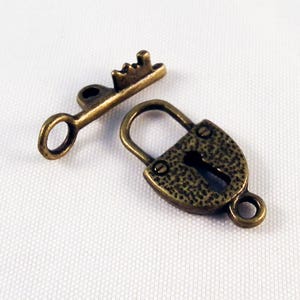May include: A small antique gold-toned padlock with a matching key. The padlock has a textured surface and a keyhole. The key has a decorative top.