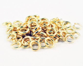 May include: A pile of gold jump rings, a type of jewelry finding used for connecting chains, cords, and other jewelry components.