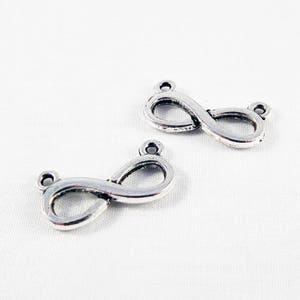 May include: Two silver infinity symbol charms with jump rings. The charms are perfect for jewellery making or adding to a keychain.