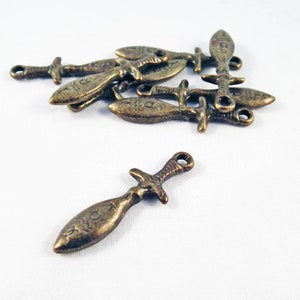 May include: A group of ten antique bronze sword charms with a loop for hanging. The swords have a detailed design and are approximately 1 inch long.
