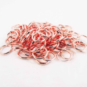 May include: A large pile of rose gold jump rings. The rings are small and delicate, perfect for jewelry making.