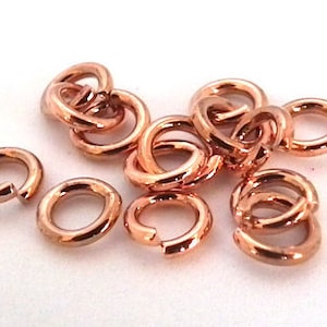 Könnte beinhalten: Nahaufnahme einer Gruppe von 10 roségoldenen Sprungringen. Die Ringe sind klein und filigran und perfekt für die Schmuckherstellung.