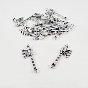 May include: Silver axe charms with intricate designs. The charms have a loop at the top for attaching to jewelry or other crafts.