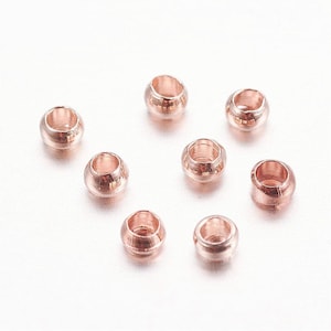 May include: A set of eight rose gold-colored metal beads. The beads are round and have a smooth, polished finish.