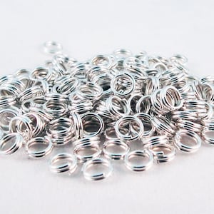 May include: A large pile of silver jump rings. The rings are small and round, and they are ideal for jewellery making.
