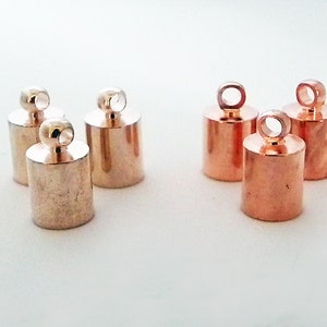 May include: Six gold-toned metal end caps with a loop at the top. The end caps are cylindrical in shape and have a smooth, polished finish.