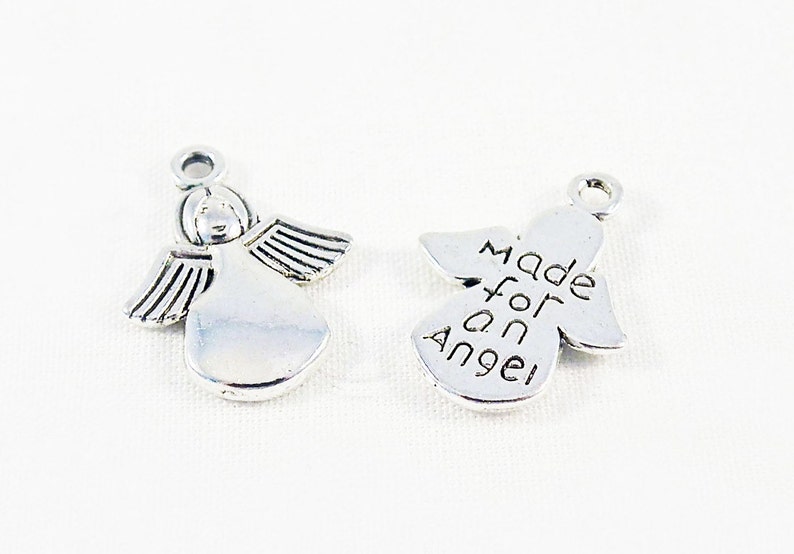 May include: Two silver angel charms. One charm features a detailed angel with wings and the other charm has the words "Made for an Angel" engraved on it.
