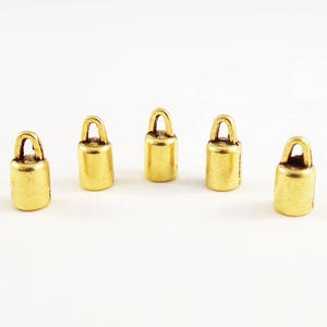 May include: Five gold-colored metal cord ends with a loop on top. The cord ends are cylindrical in shape.