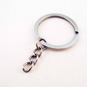 Peut inclure: Un porte-clés argenté avec un anneau rond et une courte chaîne attachée.